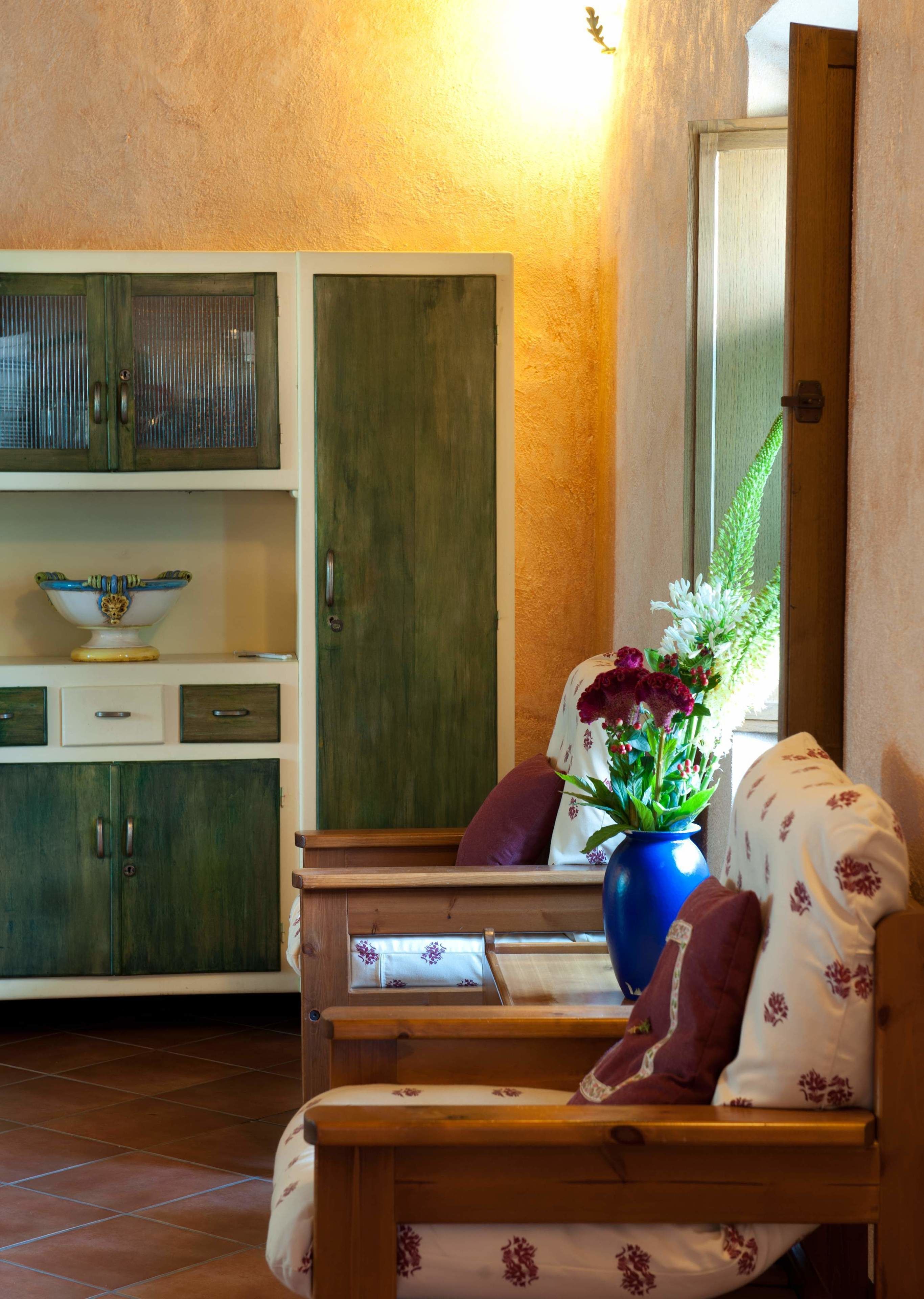 A cozy room with a wooden bench, a blue vase with flowers, and a cabinet with a bowl on top.