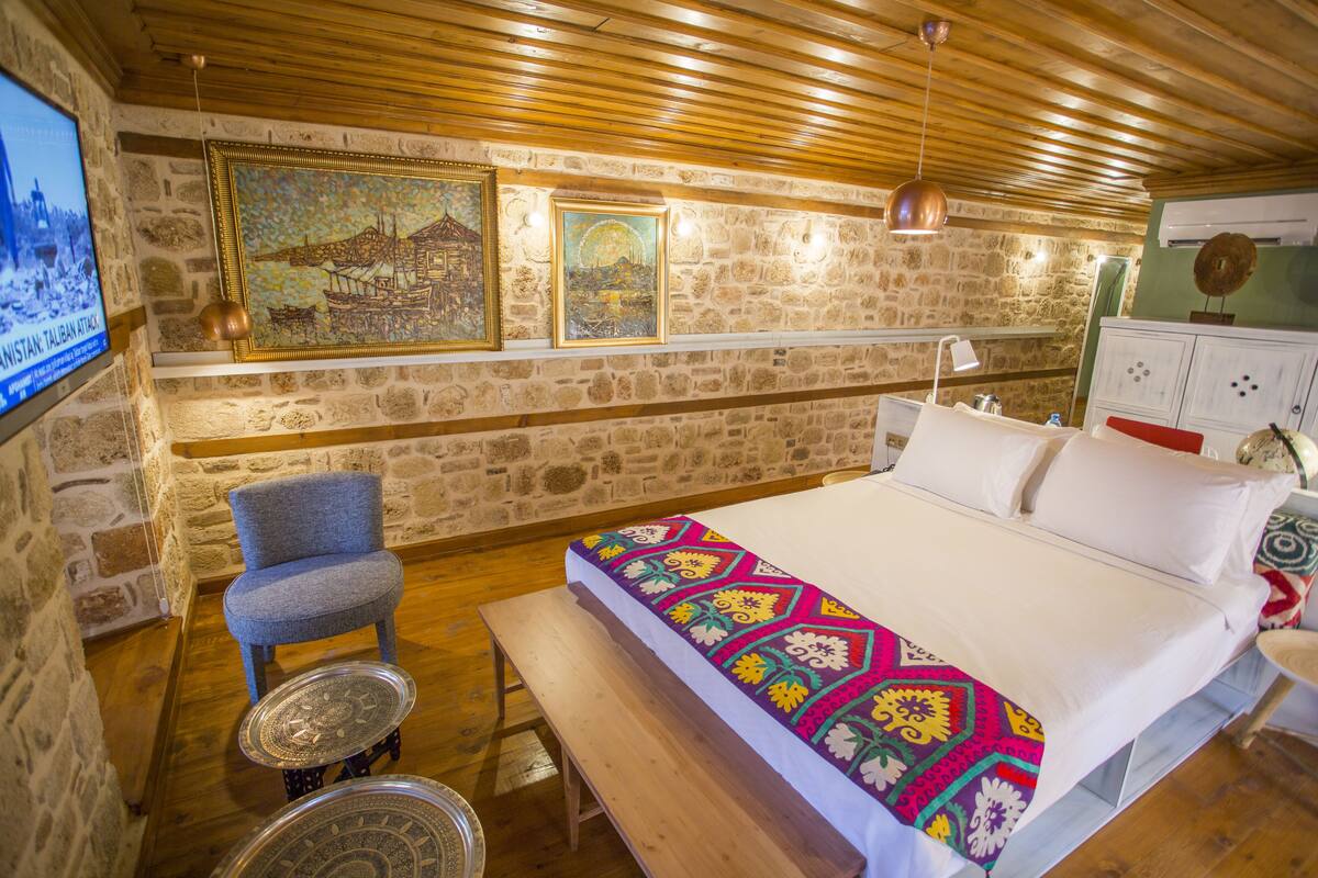 Ein gemütliches Zimmer mit einem Bett, einem Sessel, einem Tisch und einem an der Wand befestigten Fernseher.