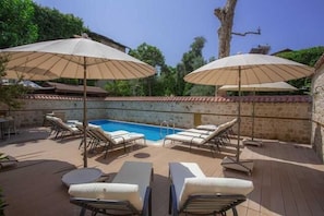 Een buitenzwembad, parasols voor strand/zwembad
