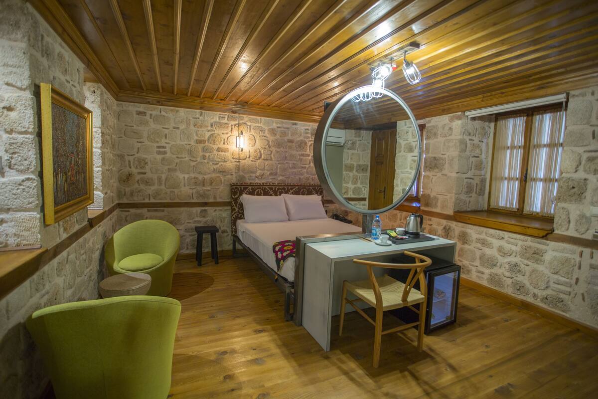 Ein Schlafzimmer mit Bett, Schreibtisch, Stuhl, Spiegel und Fenster.