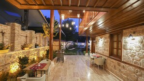 An outdoor patio with stone walls, wooden beams, and hanging lights. Tables and chairs are arranged for dining. - Charme Hotel (Antalya)