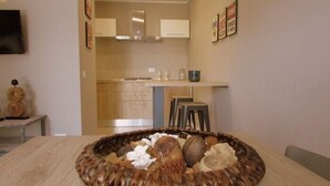 Een eethoek met een geweven mand als decoratie, een houten tafel en een keuken op de achtergrond.