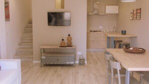 Een moderne keuken met houten kasten, een inbouwoven en een eethoek met tafel en stoelen.