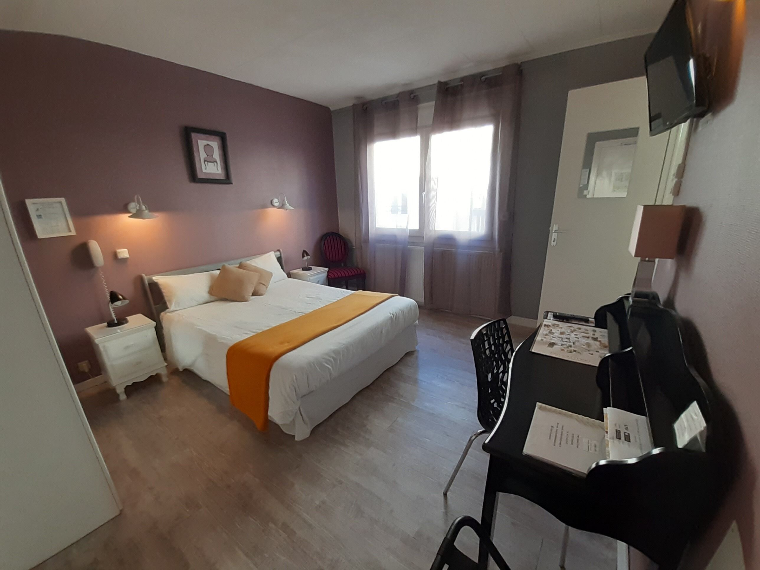 Una habitación de hotel con una cama, mesitas de noche, un escritorio y una silla.