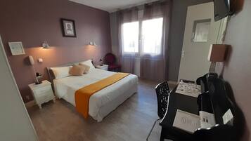 Una habitación de hotel con una cama, mesitas de noche, un escritorio y una silla.