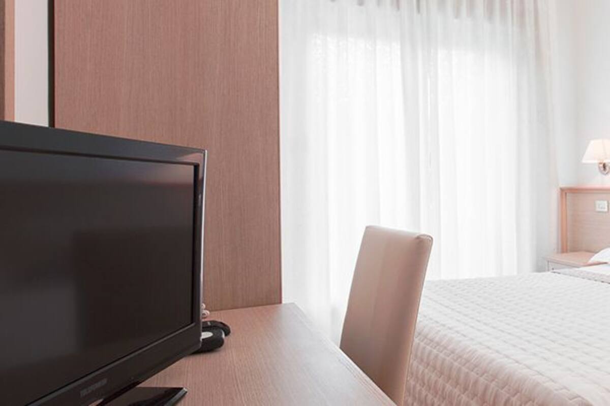 A hotel room with a bed, a TV, a chair, and a nightstand.