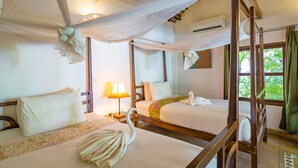 Habitación de hotel con dos camas, una cama con dosel, una mesita de noche con lámpara y una ventana con cortinas.