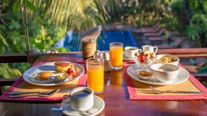 Una mesa de desayuno con platos de comida, un vaso de jugo de naranja y una taza de café.