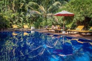 A swimming pool with yellow lounge chairs and a red umbrella. - Sambor Village Hotel (Stueng Saen)