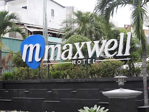 A sign for the mmaxwell hotel with a blue logo and white lettering.