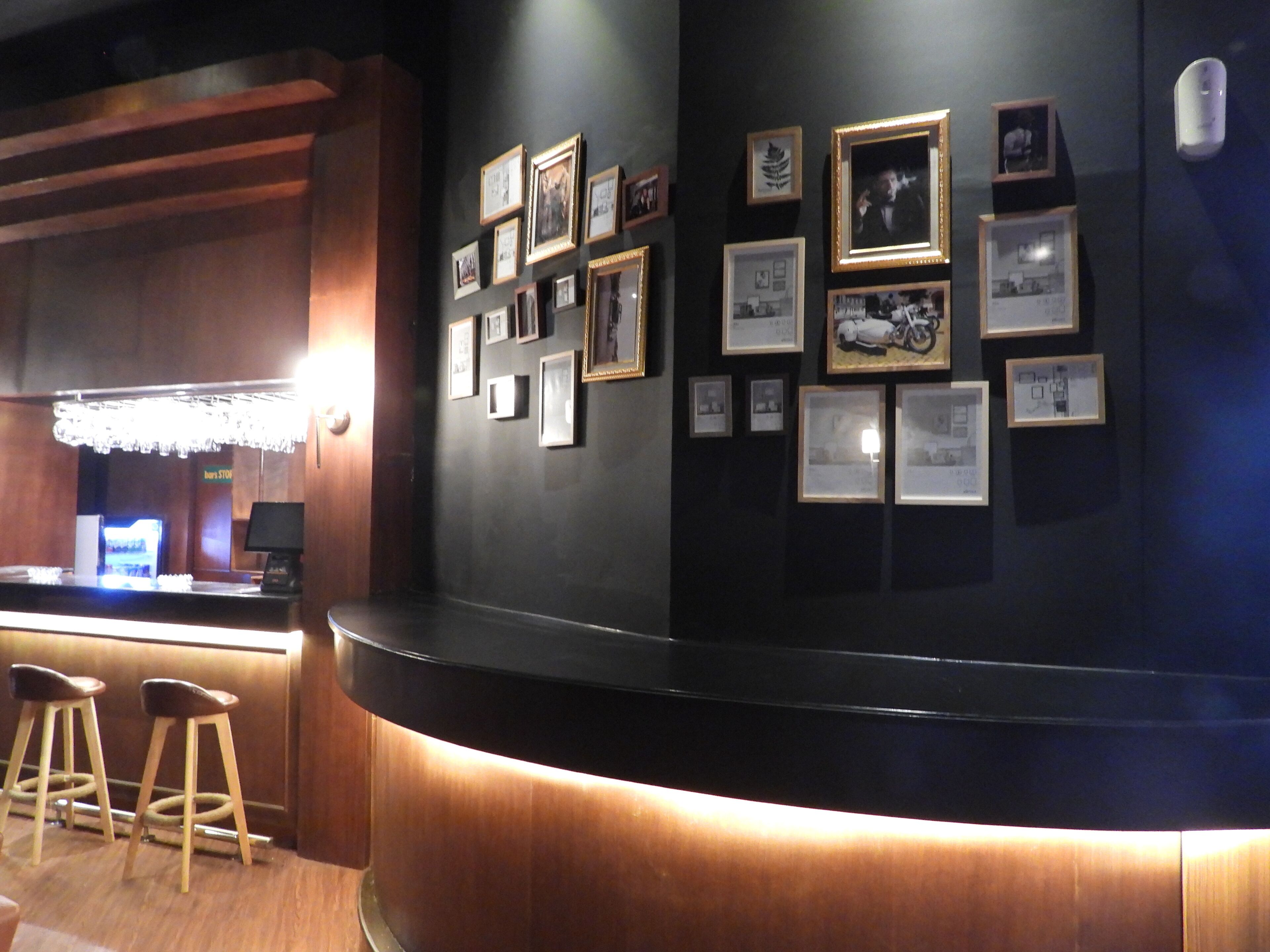 A bar area with stools, a counter, and framed pictures on the wall.