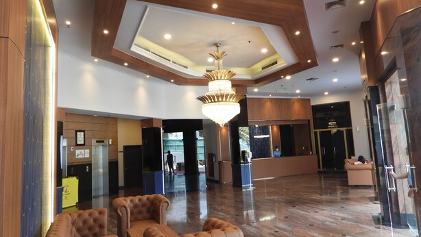 Eine großzügige Lobby mit hoher Decke, einem Chandelier und einer Rezeption.