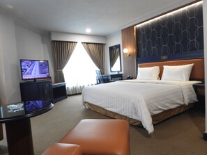 Une chambre d’hôtel comprenant un lit, un bureau, une télévision et un coin salon.