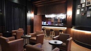 Eine Bar mit Ledersesseln, einer Theke und einer Wand mit gerahmten Bildern.