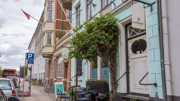 A street with parked cars, a café with outdoor seating, and a building with a sign reading "KAFFERIET." - Churchill 3BR by Daniel&Jacob's (Copenhagen)