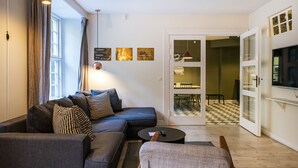 A modern living room with a sectional sofa, a round coffee table, and a view of the dining area through glass doors. - Churchill 3BR by Daniel&Jacob's (Copenhagen)