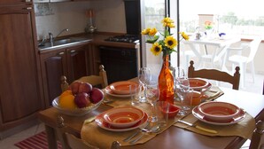 A dining table set with plates, cutlery, and a vase of sunflowers. - Residence Villa Santa Lucia (Cefalù)