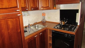 A kitchen with wooden cabinets, a stainless steel sink, a gas stove, and a dishwasher. - Residence Villa Santa Lucia (Cefalù)