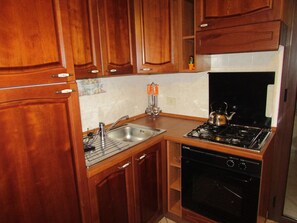 A kitchen with wooden cabinets, a stainless steel sink, a gas stove, and a dishwasher. - Residence Villa Santa Lucia (Cefalù)