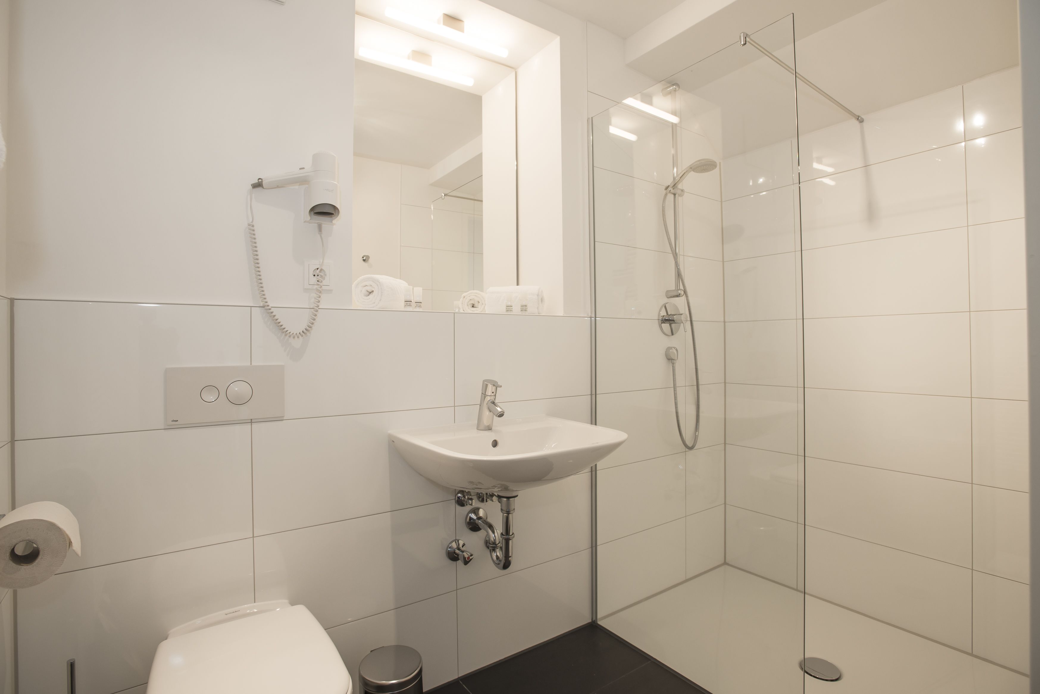 A modern bathroom with a white sink, a toilet, and a glass-enclosed shower area.