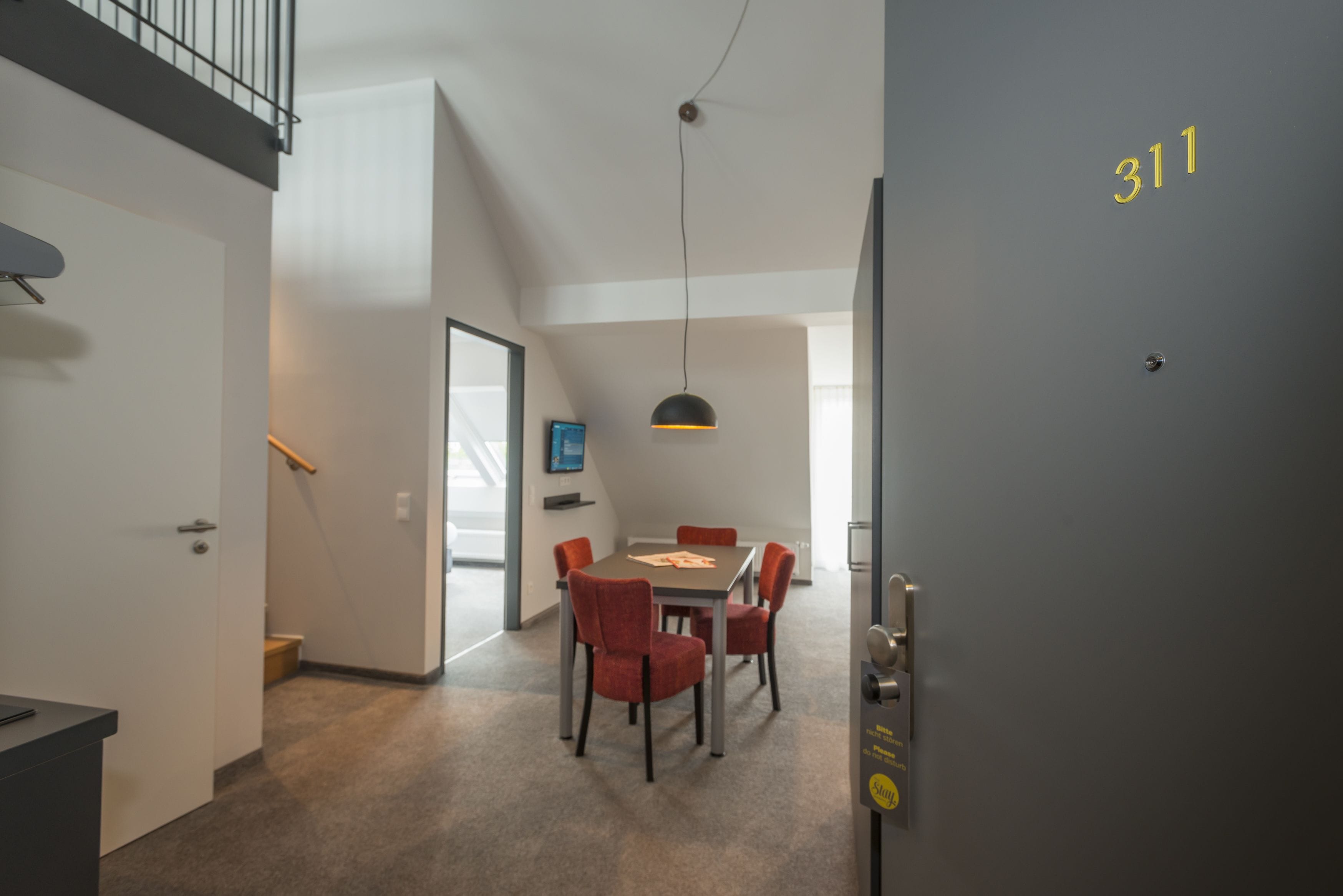 Um interior moderno com uma área de refeições, uma escada e uma porta com o número 311.