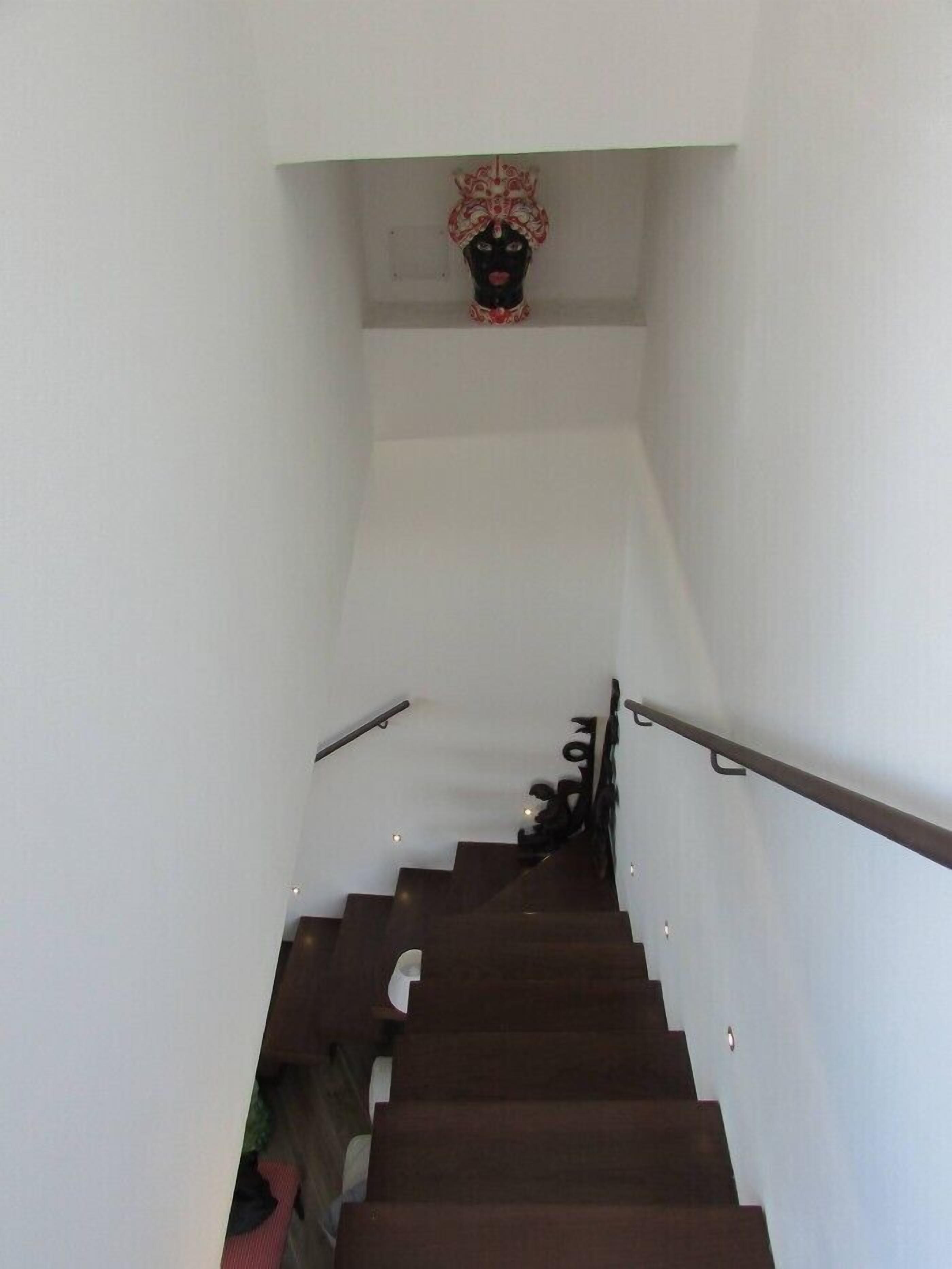 A staircase with a handrail, leading to a landing with a decorative item.