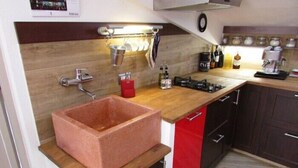 Eine kleine Küche mit einer Holz Arbeitsplatte, einem Kupferbecken und modernen Geräten.