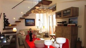 Ein modernes Wohnzimmer mit einem roten Tisch, einer Weinflasche und Gläsern. Es gibt ein Sofa, ein Schrank und ein Gemälde an der Wand.