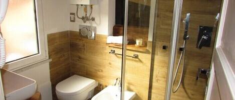 Une salle de bain moderne équipée de toilettes, d’un bidet et d’une douche à parois de verre.
