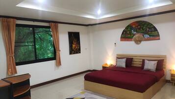 Quarto com uma cama grande, mesa de cabeceira, escrivaninha e janela com cortinas.