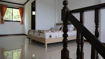 A bedroom with a wooden staircase, a bed with patterned bedding, and a window with curtains.