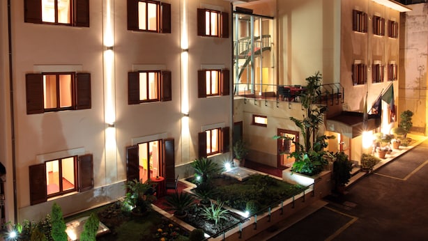 Un hotel con varias habitaciones, una escalera central y un jardín ajardinado.