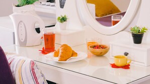 Desayuno con croissants, té y un bol de fruta sobre una encimera blanca.