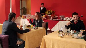 Comedor con mesas dispuestas para el desayuno, incluyendo bollería y bebidas.