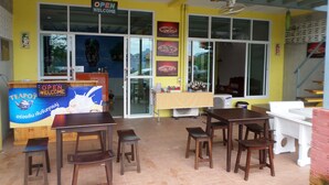 A restaurant with a yellow exterior, a sign reading "OPEN WELCOME", and a counter with a teapot and cups. - Hotel Murano Phang-Nga Bay (Phang Nga)