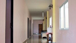 A long, narrow hallway with a reflective floor, doors on the left, and a window on the right. - Hotel Murano Phang-Nga Bay (Phang Nga)