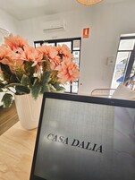Een receptiebalie met een bord waarop 'CASA DALLA' staat en een bloeiende plant in een pot.