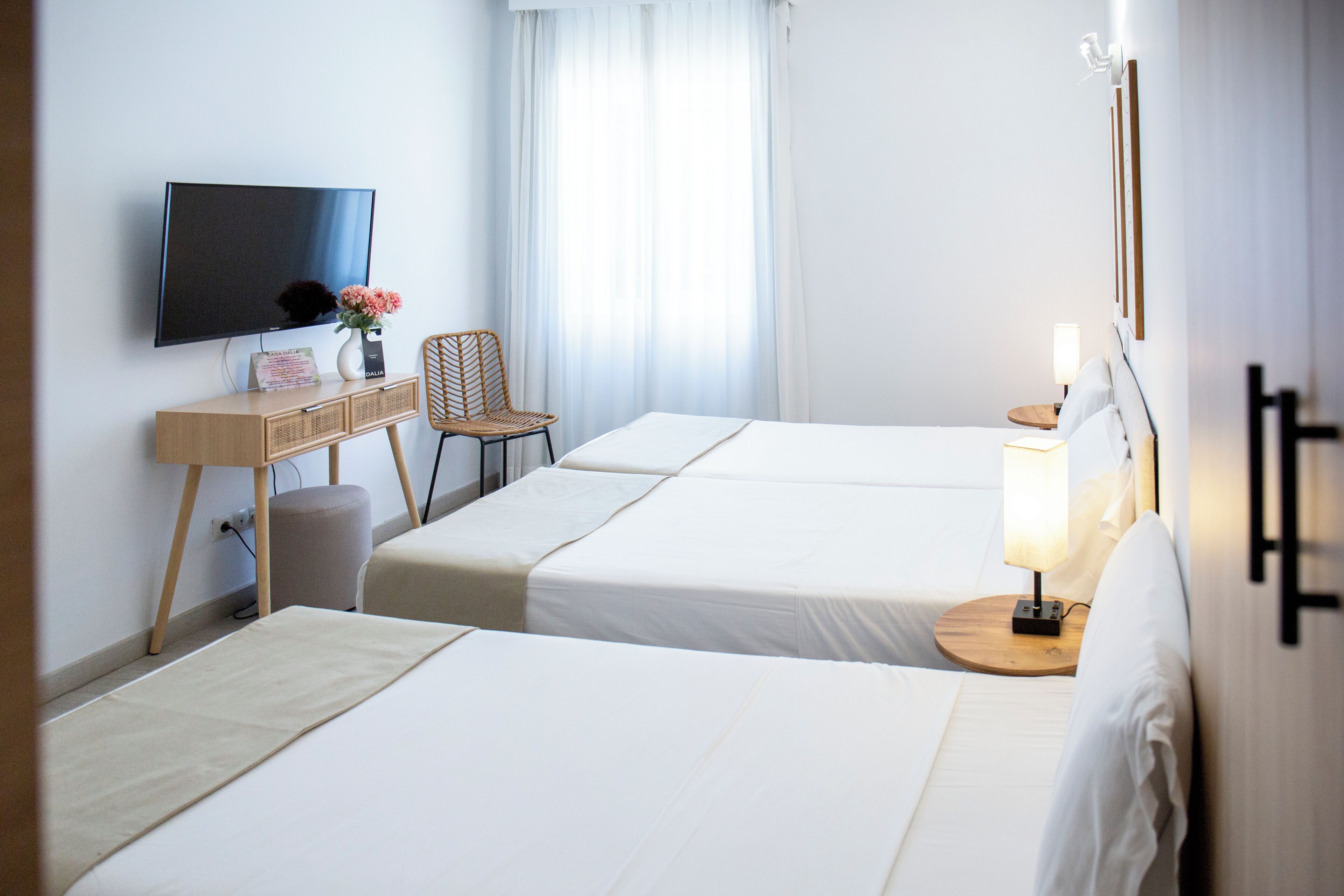 A hotel room with two beds, a TV, a desk, and a chair.
