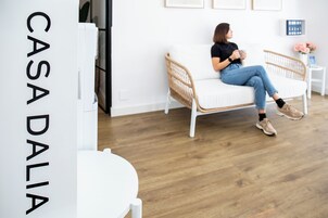 Een modern interieur met een witte bank, een rieten fauteuil en een bijzettafeltje met een bloemenvaas.