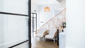 Un interior moderno con una escalera de madera, sillas de mimbre y una lámpara colgante.