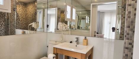 A modern bathroom with a glass shower enclosure, a wooden vanity with a sink, and a toilet.