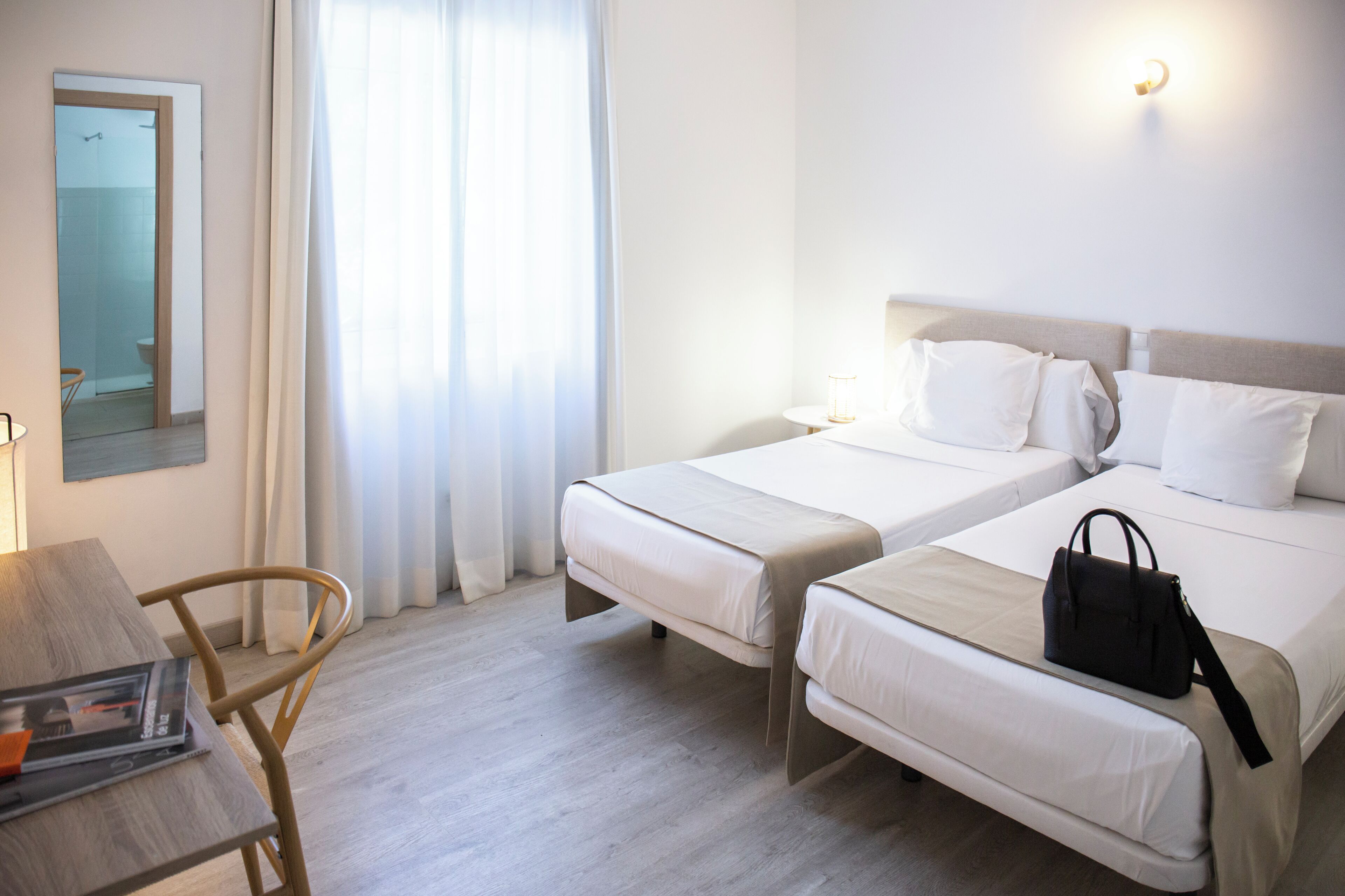 A hotel room with two beds, a desk, and a chair.