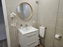 Een badkamer met een wit wastafeltje, spiegel en handdoekhouder.