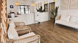 Un espacio habitable amplio con mobiliario de mimbre, un sofá blanco y una escalera de madera.