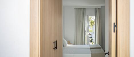 A bedroom with a bed, a wooden door, and a window with curtains.