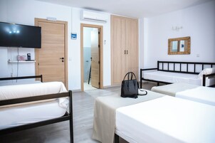 Ein Hotelzimmer mit zwei Einzelbetten, einem Fernseher, einem Kleiderschrank und einem Spiegel.