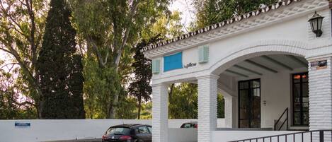 A white building with a covered entrance and a blue sign.