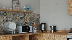 Eine Küche mit Mikrowelle, Kaffeemaschine und Wasserkocher auf der Arbeitsplatte und einer gefliesten Spritzschutzwand.
