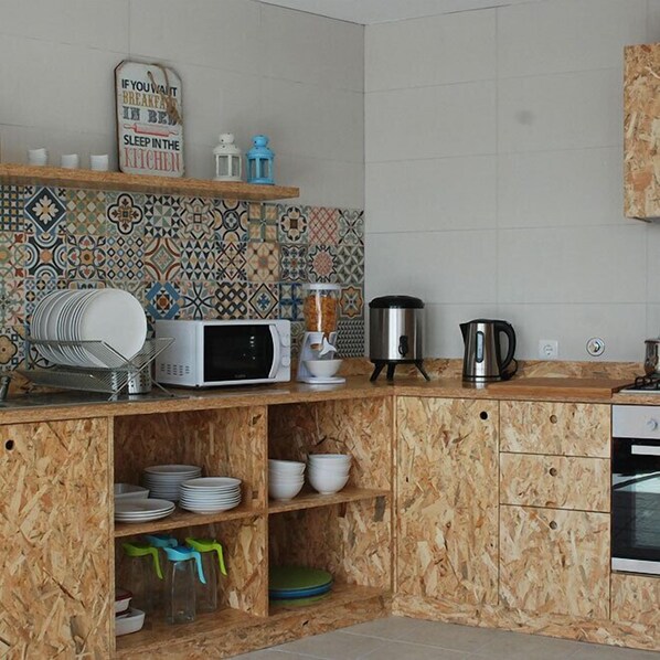 A kitchen with a microwave, coffee maker, and kettle on the counter, and a tiled backsplash. - Esposende Guesthouse - Hostel (Esposende)