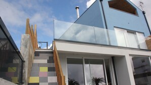 Ein modernes Haus mit blauer Fassade, einer Treppe mit Schachbrettmuster und einer großen Glasdoor.